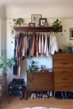 a bedroom with clothes hanging on a rack and shoes in front of the closet door