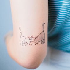 a woman's arm with a cat and dog tattoo on the left side of her arm