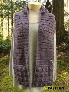 a woman wearing a purple crocheted vest in front of a forest with trees