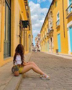 a woman sitting on the ground in front of yellow buildings