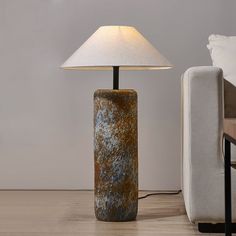 a lamp sitting on top of a wooden floor next to a couch