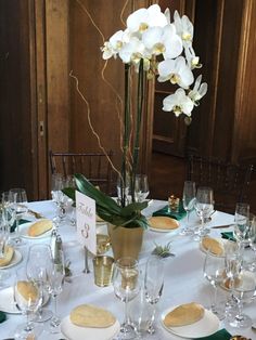 the table is set with white flowers and place settings