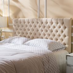 the headboard of a bed with white sheets and pillows in a hotel room setting