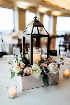 a lantern with flowers and candles on a table