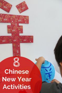 a young boy holding a paper ball in front of a chinese new year activity sign