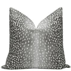 a gray and white pillow with black spots on the front, sitting on a white background