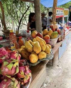 there are many different types of fruit on display at this market stall, including dragon fruit and mangoes