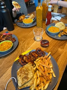 three plates with food on them sitting on a table next to drinks and condiments