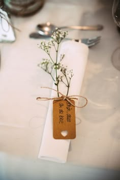 a place setting with silverware, napkins and flowers on the table for guests to enjoy