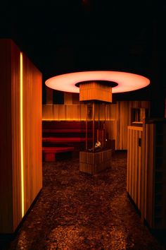 a dimly lit room with wooden walls and red lights on the ceiling, along with benches