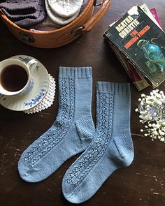 two pairs of blue socks sitting on top of a table next to a cup of coffee