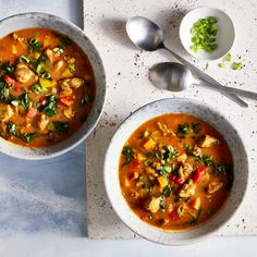 two bowls of soup on a table with spoons