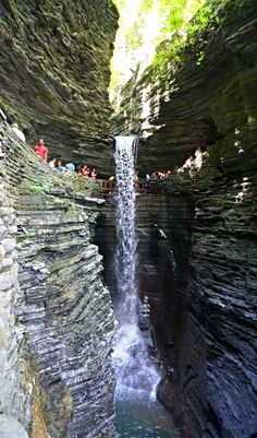 people are standing at the base of a waterfall