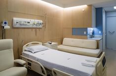 a hospital room with a bed, couch and medical equipment on the wall next to it