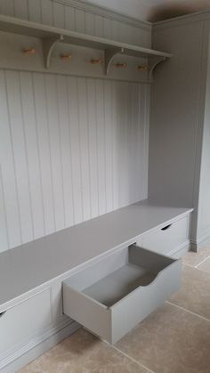 a white bench with drawers underneath it in the middle of a floored room that has beige tile floors