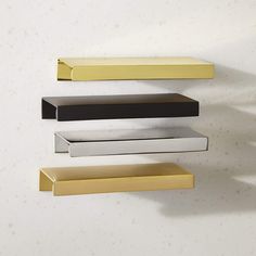 three metal shelves on the wall, one is black and one is gold in color