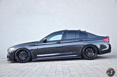 a gray car is parked in front of a white wall with black rims and chrome wheels