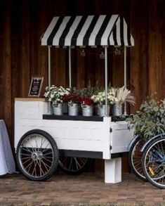 two bicycles are parked next to a table with flowers on it and an awning