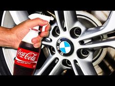 a man is cleaning the rim of his car wheel with a spray bottle and cloth