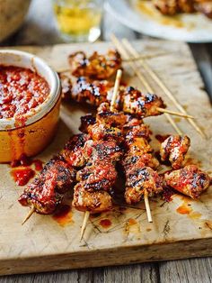 chicken skewers with marinara sauce and toothpicks on a cutting board