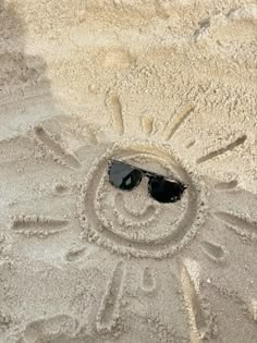 a smiley face drawn in the sand with sunglasses