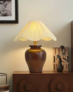 a table lamp sitting on top of a wooden cabinet next to a vase and other items