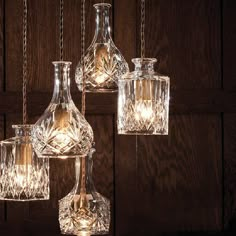 three clear glass vases with lights hanging from them