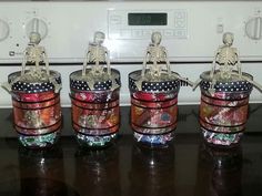 four glass jars with skeletons in them sitting on top of a counter next to an oven