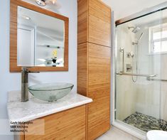 a bathroom with a glass bowl sink under a mirror and wooden cabinetry, along with a walk in shower