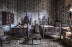 an old fashioned bedroom with four poster bed and two chairs in the room, all covered by floral wallpaper