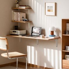 a laptop computer sitting on top of a wooden desk next to a book shelf filled with books