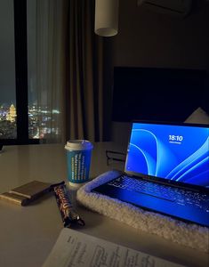 an open laptop computer sitting on top of a desk next to a cup of coffee