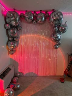 a room with disco balls and streamers hanging from the ceiling in front of a pink curtain