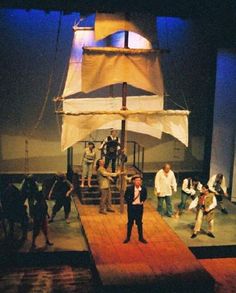 a group of people standing on top of a wooden platform in front of a boat