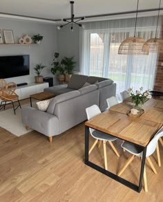 a living room filled with furniture and a flat screen tv mounted on the wall above a wooden table