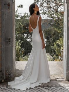 a woman in a white wedding dress looking out an open door