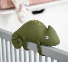 a green stuffed animal laying on top of a radiator next to a baby crib