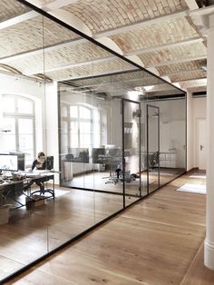 an empty office with glass walls and wooden floors is pictured in this image from the inside