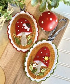 two decorative plates with red mushrooms on them next to a potted plant and an apple