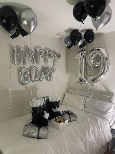 balloons and gifts on a bed with the words happy birthday hanging from the headboard