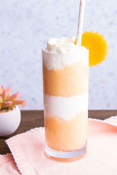 a drink with whipped cream and an orange slice on the top is sitting on a pink napkin