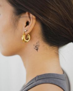 a woman with a small tattoo on her neck and behind her ear is a butterfly