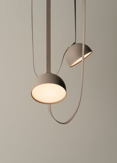 two light fixtures hanging from the ceiling in a room with gray walls and flooring