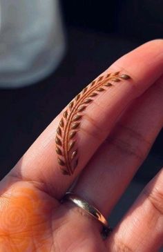 a person's hand with a ring on it that has a leaf design in the middle