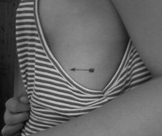 a woman with a small arrow tattoo on her chest