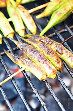 grilled corn on the cob and green beans are being cooked over an open charcoal grill