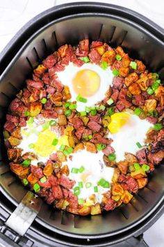 an open air frying pan with eggs and meat in it on a white surface