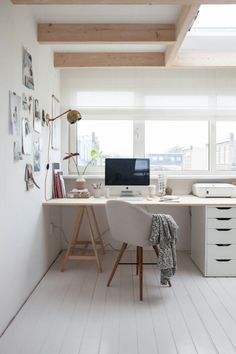 an office with white walls and wooden floors is pictured in this image, there are two computer screens on the desk