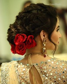 a woman with red roses in her hair and some beads on her neck, wearing a gold