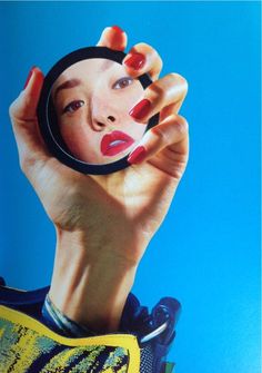 a woman's hand holding up a magnifying glass in front of her face